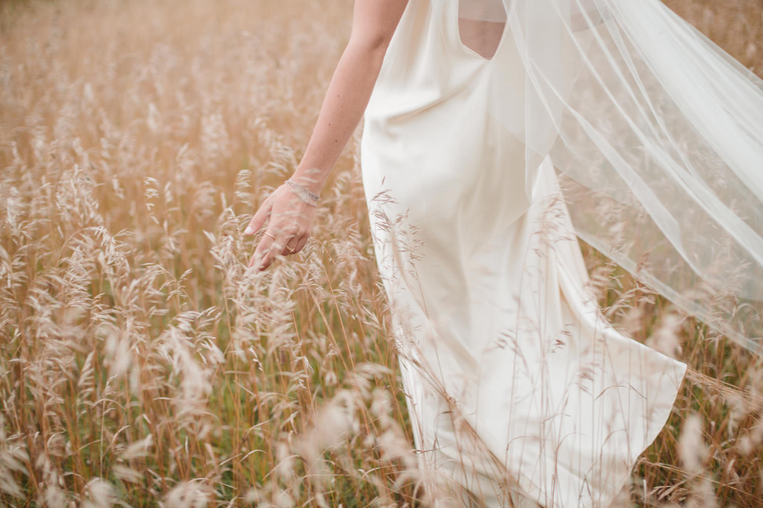 Bride walking through long grass at Braestone farm